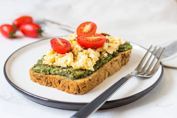 Omlet ve avokado ve kiraz domates ile kepekli ekmek üzerinde.