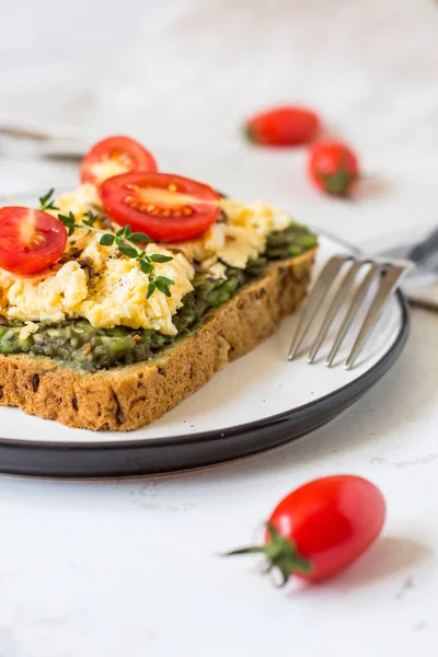 Omlet ve avokado ve kiraz domates ile kepekli ekmek üzerinde.