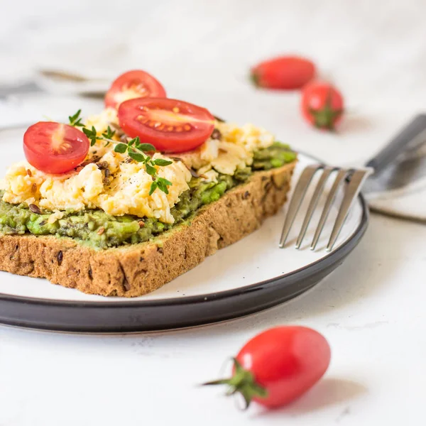 Omlet ve avokado ve kiraz domates ile kepekli ekmek üzerinde.