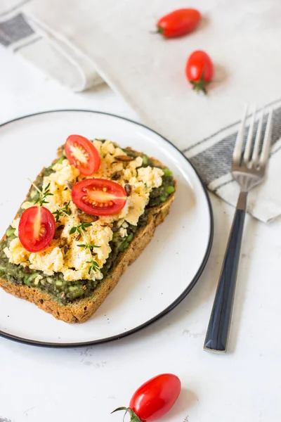 Omlet ve avokado ve kiraz domates ile kepekli ekmek üzerinde.