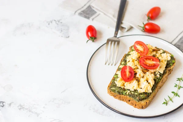 Omlet ve avokado ve kiraz domates ile kepekli ekmek üzerinde.