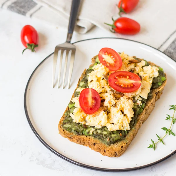 Omlet ve avokado ve kiraz domates ile kepekli ekmek üzerinde.
