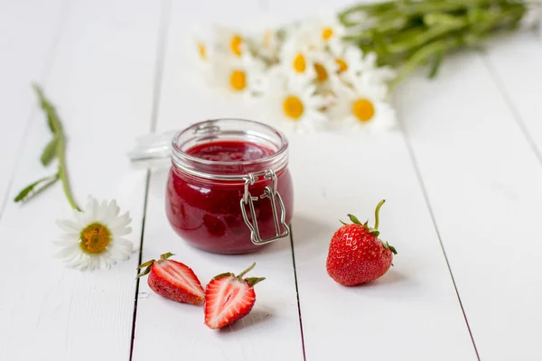 Aardbeienjam in een glazen pot op een tafel met chamomiles — Stockfoto