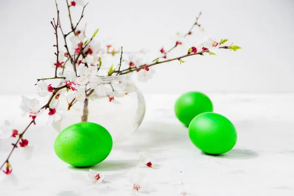 Grüne Ostereier mit blühenden Zweigen auf dem Tisch — Stockfoto