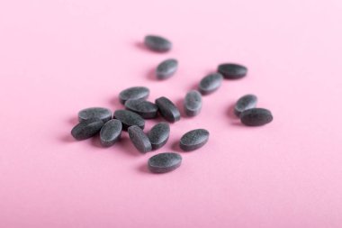 Spirulina tabletler, pembe arka plan üzerinde klorofil 