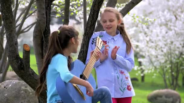 少年女孩演奏牛仔裤吉他并且唱歌入公园春天 — 图库视频影像