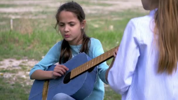 Kisgyermek Lány Énekes Kalimpálás Akusztikus Gitár Miközben Barátnője Állandó Hallgató — Stock videók