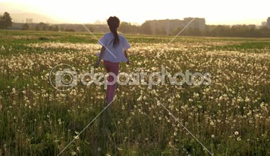 çekici küçük kız çalışır ve alanı ile eğleniyor ve hayatın tadını çıkarırken dandelions atlar tatil yaz. geri kalan Şehir Park çiçekli sezon yeri. duygu ve ruh hali