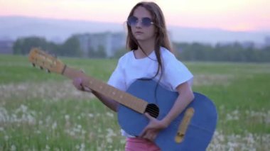 şirin hippi gitar açık içinde güneş gözlüğü üzerinde küçük kız gün batımı ilkbahar yakınındaki şehir. duygular ve pop sanatçı taklit. yaratıcılık ve yaşam tarzı kavramı