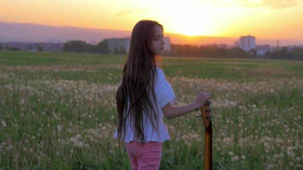 Bei Sonnenuntergang Hält Das Kleine Musikermädchen Mitten Auf Dem Feld — Stockvideo