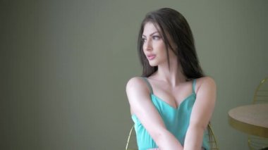 çok güzel genç kadın kameraya, seyir poz model bir sandalye ve doğru uzun kahverengi oturma saç modelleri