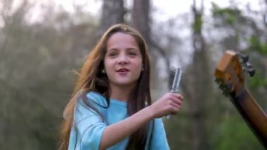 küçük kız parkta bahar günü iyi eğlenceler. aptal şarkı şarkıları ve birlikte gitar çalmak dans oyun