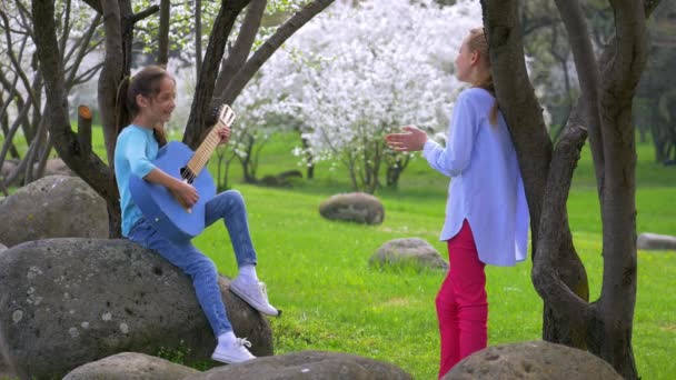 Zwei Fröhliche Kleine Freundinnen Die Park Auf Der Gitarre Musizieren — Stockvideo