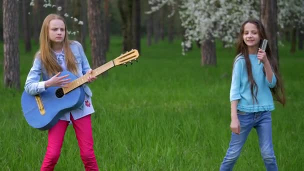 在森林里弹奏吉他音乐的年轻小女孩公园跳舞会让人感到有趣 愚弄周围 欢欣春天的假期 — 图库视频影像