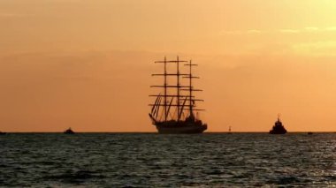 Üç direkli tam konulan uzun gemi gündoğumu bir yaz sabahı, kıyıya yakın. siluet turistik gemi limanda yüzen