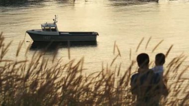 Gün batımında powerboat koy güzel manzarasına, babası tutan oğlu onun kollarında onu liman gösterir ve onu öper