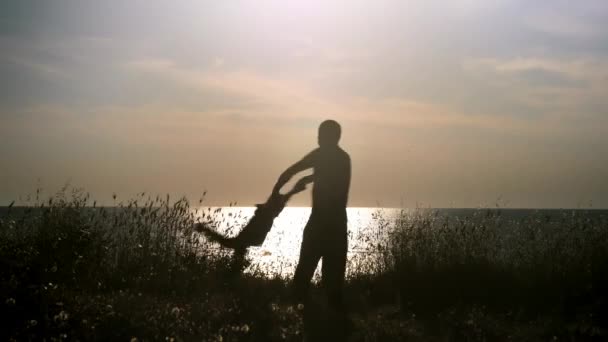 幸福的父亲和儿子在日落时在海滩上玩耍 爸爸拿着他的孩子的手 旋转他周围 — 图库视频影像