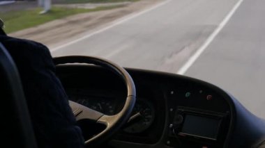 Vücudunun bir parçası elleri otobüs ya da kamyon sürüyor. Araç kontrol makinesinde direksiyon tutan profesyonel sürücü kabinin içinden gelen otoyola bakıyor..