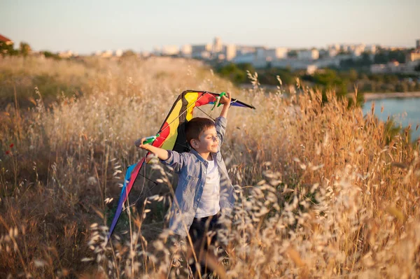 Gelukkig heerlijk glimlachend klein kind met vlieger in handen staan op zomerveld nea zeehaven buiten stad met gesloten ogen met plezier — Stockfoto