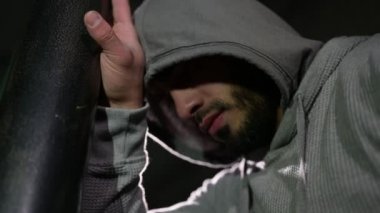 Kapüşonlu güçlü genç sakallı adam spor yaparken eğiliyor.