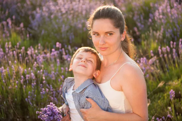 Bela família feliz jovem mãe abraçando seu filho sorridente no verão roxo lavanda campo de flores — Fotografia de Stock