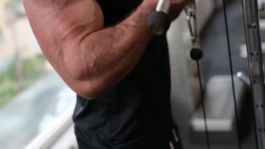 Güçlü genç erkek sporcu spor kasları eğitimi sırasında spor aletleri kullanarak ağırlık kaldırıyor.