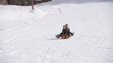 Dışarıda tatil yaparken kar yamacında metroyla gezen mutlu çocuklar. Boş vakitler için tüpler.