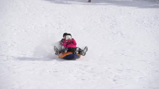 快乐的家庭穿着滑雪服，父亲和孩子们坐着雪管在休闲度假胜地的山冬坡上开车 — 图库视频影像