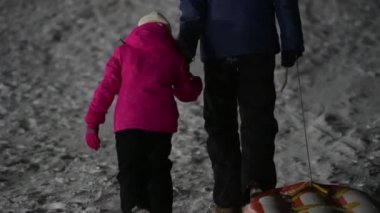 Aktif mutlu aile çocuğu ve kauçuk tüplü erkek babası kış yamacında gece dağlarında yürüyorlar.