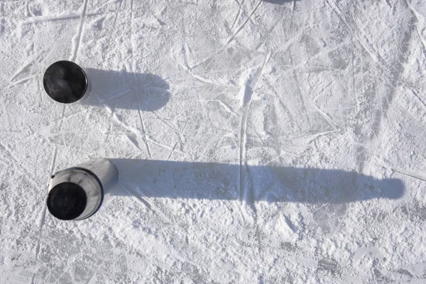 an open thermos stands on ice with a cup of hot tea