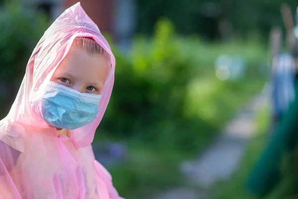 Portrait of a child in protective clothing and a medical mask on the street in summer. Prevention against coronavirus and Covid-19 during a pandemic