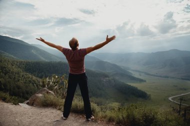 Genç adam bir kaya üzerinde duruyor ve valley adlı görünüyor. Dağlarda trekking