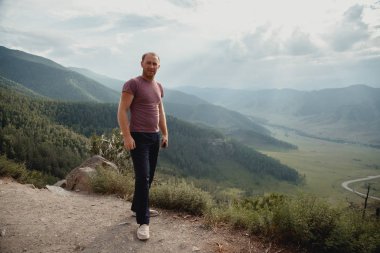 Genç adam bir kaya üzerinde duruyor ve valley adlı görünüyor.