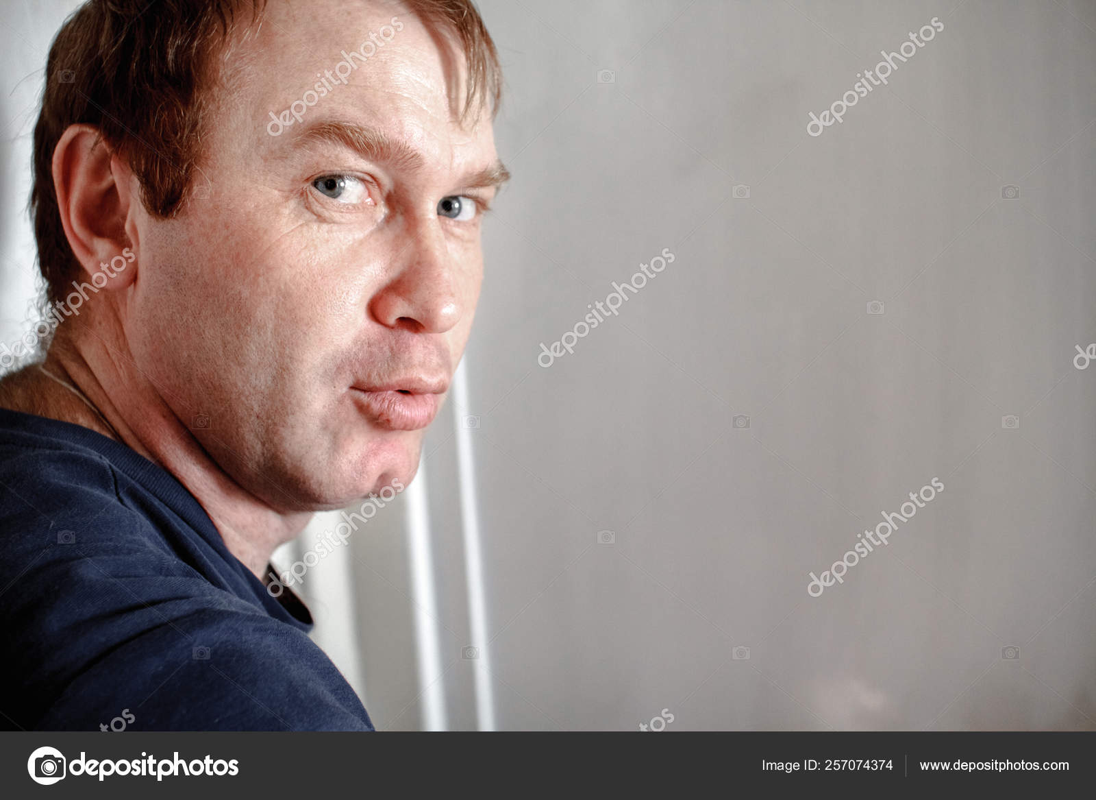 A Red Haired Man With Freckles On A White Background Turned His