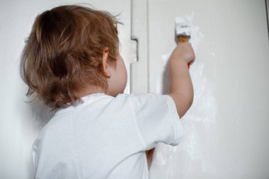 Beyaz tişörtlü yaramaz bir kız duvarı beyaz boyayla boyadı..