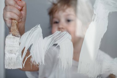 Çocuk cam bir tahtaüzerine beyaz bir boya çizer. Simüle ekran. Fırça ile mutlu çocuk