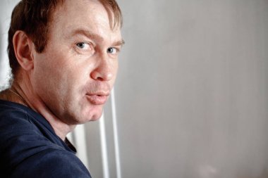 Beyaz arka planda çiller olan kızıl saçlı bir adam kafasını kameraya çevirdi. Sorgulama bakışı