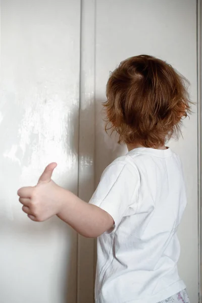 Uma menina safada em uma camiseta branca pinta a parede com tinta branca. mostra classe . — Fotografia de Stock