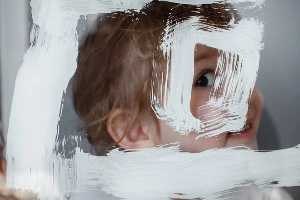 Çocuk bir cam tahta üzerinde beyaz boya ile güneş çizer. Simüle ekran. Göz deliğe bakar