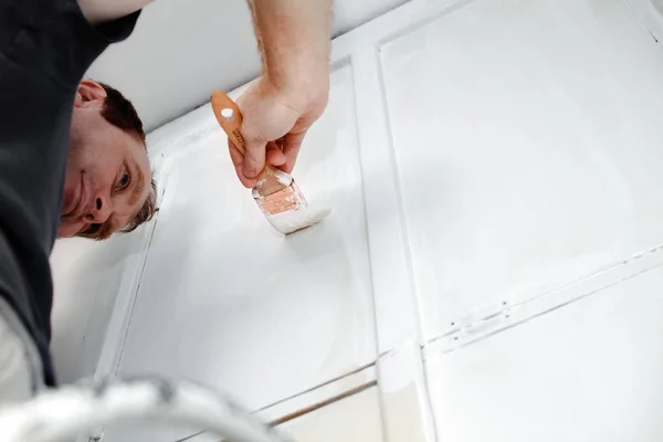 A man paints the wall with white paint in the apartment. Repair your home — Stock Photo, Image