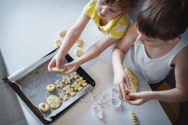 İki çocuk fırın tepsisine kurabiye koyar. ev yapımı tatlılar. Yukarıdan görünüm