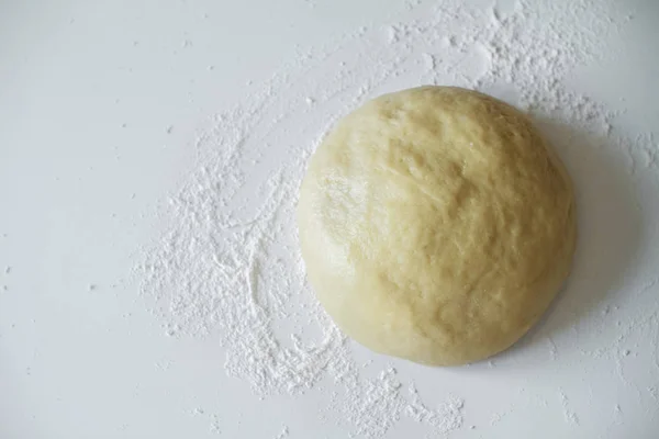 Beyaz bir arka plan üzerinde masanın üzerinde yatan çiğ hamur. Ekmek pişirmek için bir parça hamur. Makarna hamuru. Shortbread — Stok fotoğraf