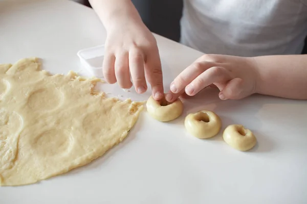 Copilul face matrițe de cookie-uri pe o masă albă. Prepararea desertului de casă. Închide — Fotografie, imagine de stoc