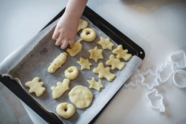 两个孩子把饼干放在烤盘上。自制甜点。顶部的视图 — 图库照片