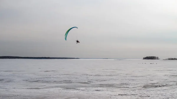Paraglider met motor vliegt over de zee, die is bedekt met ijs en sneeuw. Gratis vlucht in de winter — Stockfoto