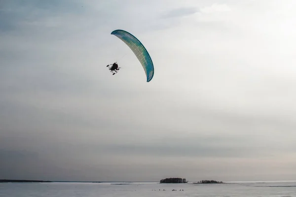 Paraglider met motor vliegt over de zee, die is bedekt met ijs en sneeuw. Gratis vlucht in de winter — Stockfoto