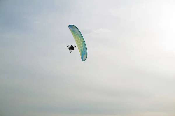 Paraglider with motor flies over the sea, which is covered with ice and snow. Free flight in winter