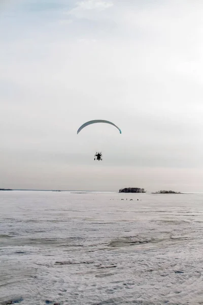 Paraglider met motor vliegt over de zee, die is bedekt met ijs en sneeuw. Gratis vlucht in de winter — Stockfoto