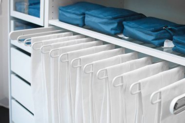 Dolaptaki eşyaların saklanması ve evdeki düzen. Beyaz şeyler düzgünce pantolon için bir askı asılı.
