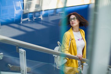 Yaz satış konsepti. Ücretsiz kopya alanı ile mavi arka plan üzerinde alışveriş merkezinde sarı ceket ve gözlük şık genç kız